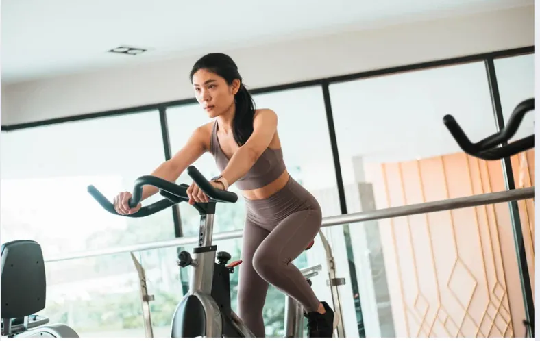 Femme qui pédale sur un vélo d’appartement à la maison